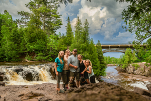 Laura Gardner and her family centered among trees with bridge and river behind them