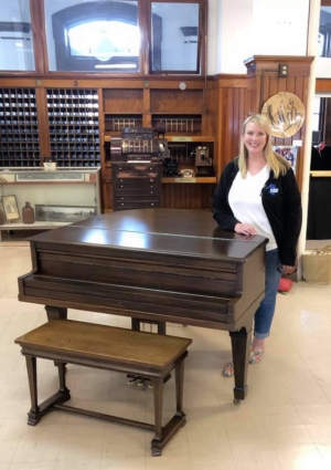 Lisa Crosby standing behind baby grand piano 