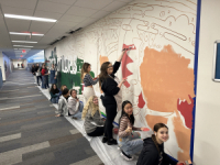 Watford City High School students painting a mural on a wall